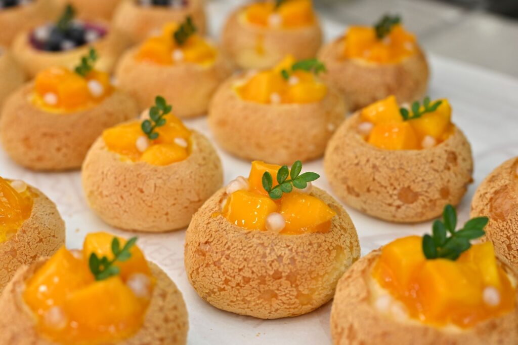 Délicieuses pâtisseries choux à la crème de mangue surmontées de feuilles décoratives fraîches pour l'inspiration dessert.