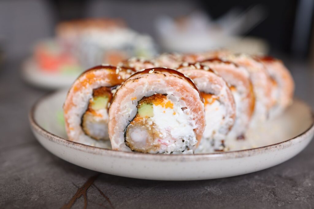 Gros plan alléchant de rouleaux de sushi au saumon et à l'avocat présentés sur une assiette en céramique magnifiquement travaillée.