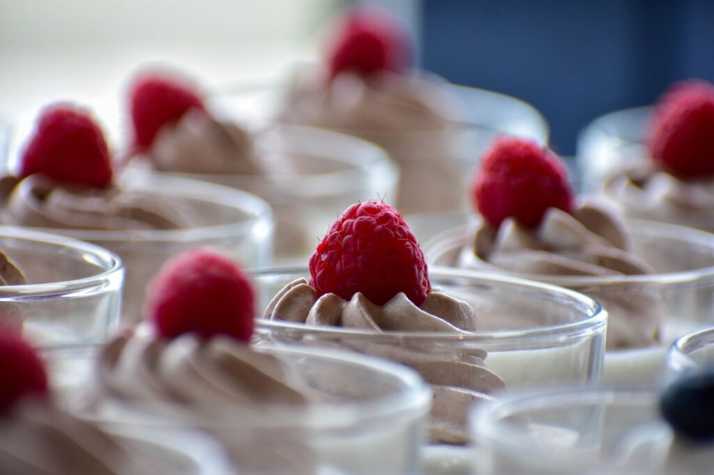 Savourez de délicieux desserts à la framboise surmontés dans des coupes en verre, parfaits pour les envies sucrées.