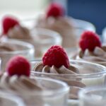Savourez de délicieux desserts à la framboise surmontés dans des coupes en verre, parfaits pour les envies sucrées.