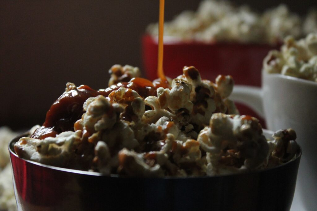 Une image en gros plan montrant du caramel versé sur du pop-corn dans des bols colorés.