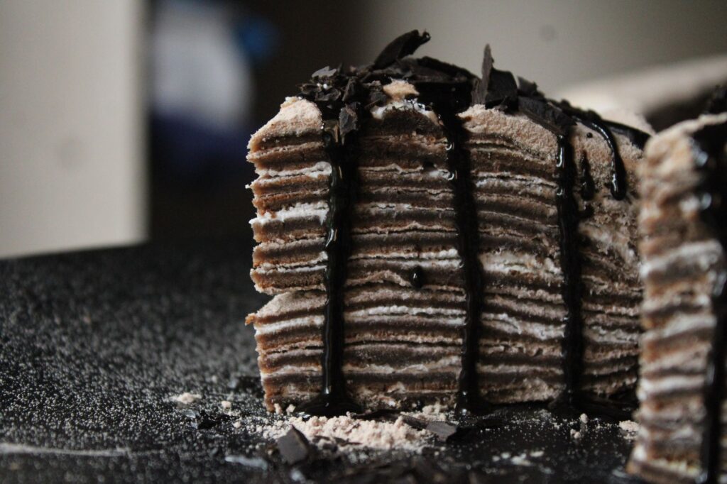 Gros plan sur un gâteau au chocolat à plusieurs étages, recouvert d'une ganache noire et de copeaux de chocolat.