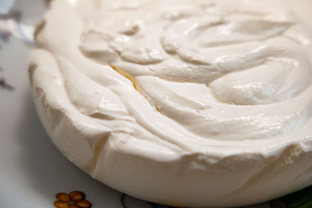 Gros plan délicieux d'un dessert meringué aérien à la texture brillante, présenté sur une assiette décorative.