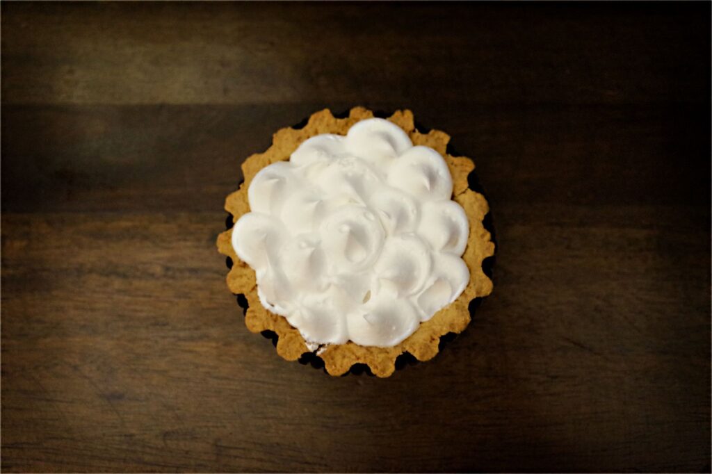 Vue de dessus d'une tarte crémeuse au citron meringuée sur une table rustique en bois, mettant en valeur son design complexe.