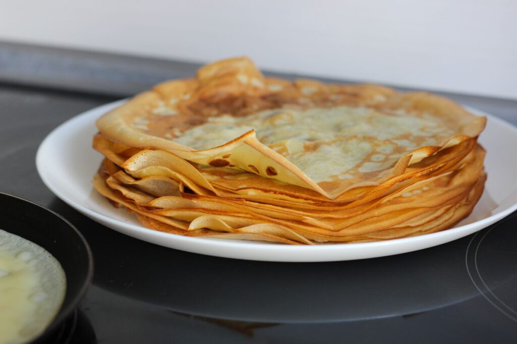 Une délicieuse pile de crêpes dorées sur une assiette blanche, parfaite pour le petit-déjeuner ou le dessert.