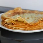 Une délicieuse pile de crêpes dorées sur une assiette blanche, parfaite pour le petit-déjeuner ou le dessert.