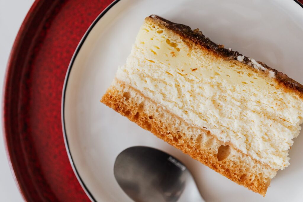 Une part savoureuse de cheesecake en couches servie sur une assiette avec une cuillère, parfaite pour les amateurs de dessert.