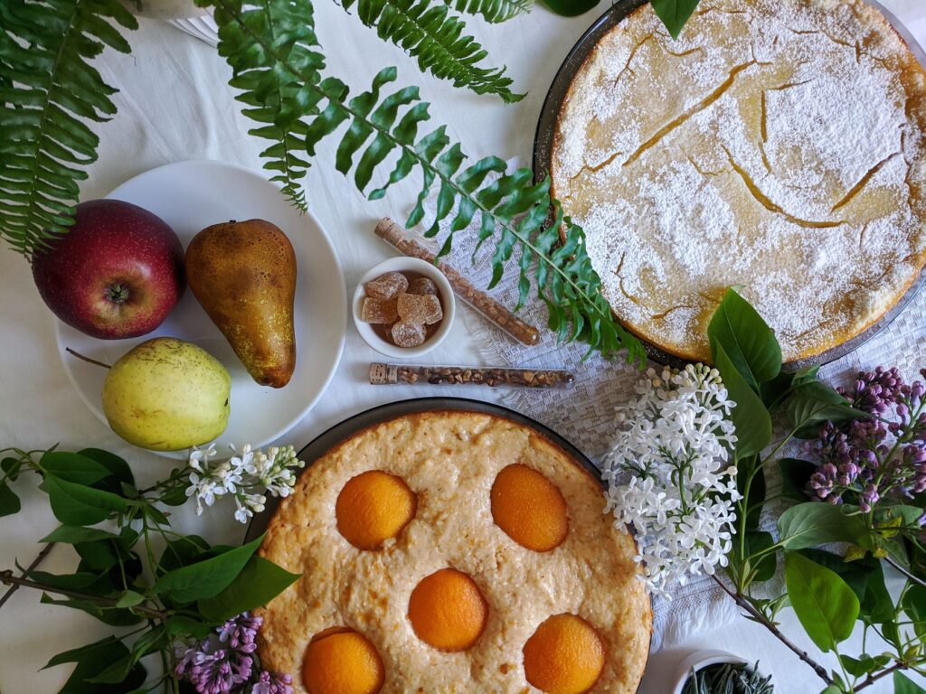 Une composition artistique de tartes avec des fruits frais, entourées de fougères et de fleurs, parfaite pour les amoureux de la gastronomie.