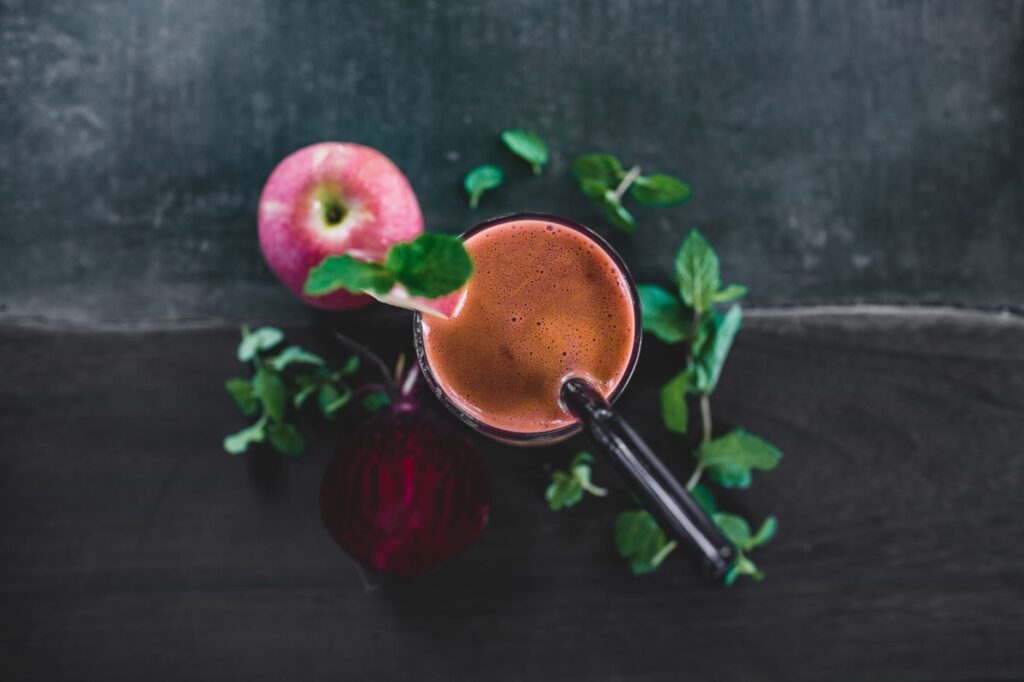 Une vue plongeante d'un smoothie sain à la pomme et à la betterave, garni de feuilles de menthe, parfait pour une détox et pour se rafraîchir.
