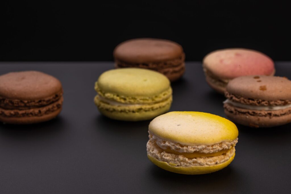 Délicieux macarons assortis aux couleurs vives présentés sur un fond sombre.