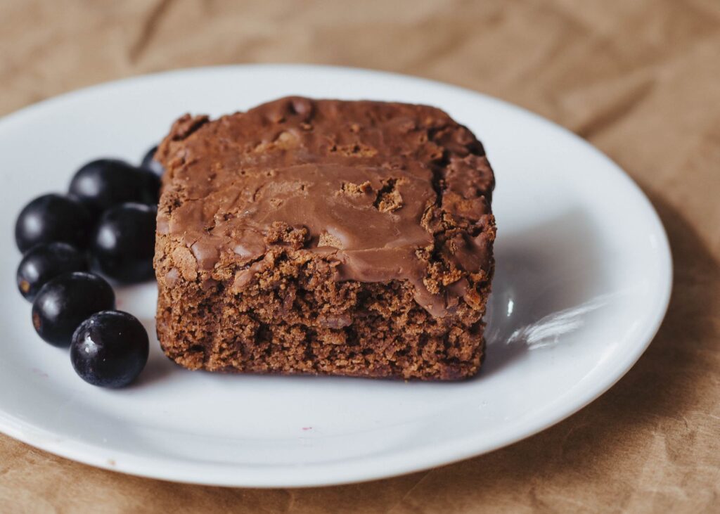 Gros plan d'un brownie au chocolat sur une assiette blanche avec des myrtilles fraîches.