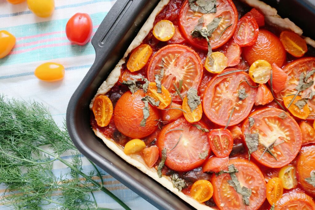 Tarte savoureuse aux tomates avec du basilic frais et des tomates cerises colorées, parfaite pour un repas d'été.