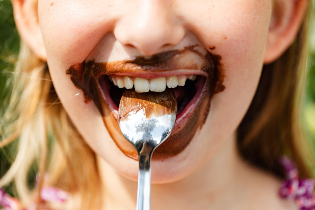 Gros plan sur le visage d'un enfant dégustant une friandise au chocolat, souriant avec une cuillère.