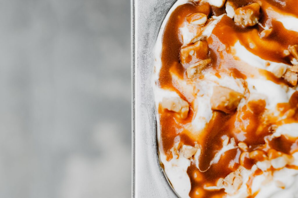 Gros plan sur une crème glacée crémeuse garnie de sauce caramel riche et de noix, parfaite pour les amateurs de dessert.