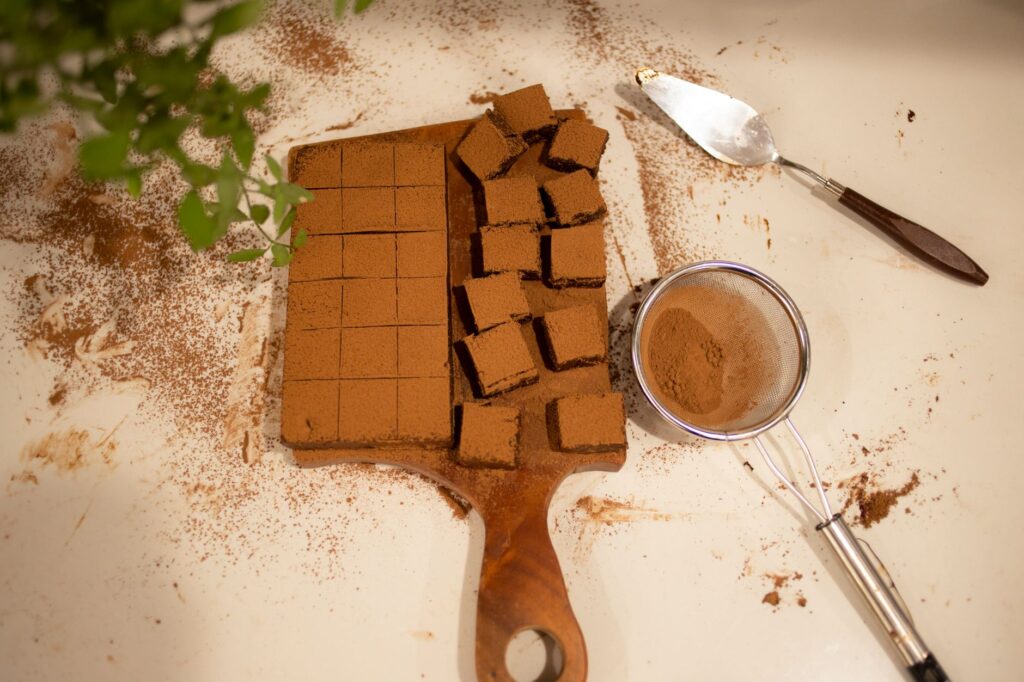 Vue de dessus de brownies au chocolat fraîchement coupés sur une planche en bois avec des ustensiles de cuisson.