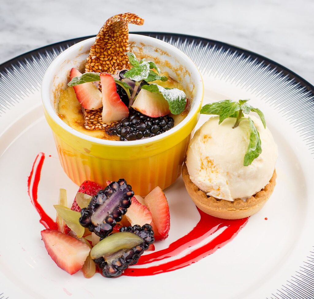 Faites-vous plaisir avec une crème brûlée gourmande surmontée de mûres et de fraises, accompagnée d'une glace à la vanille.