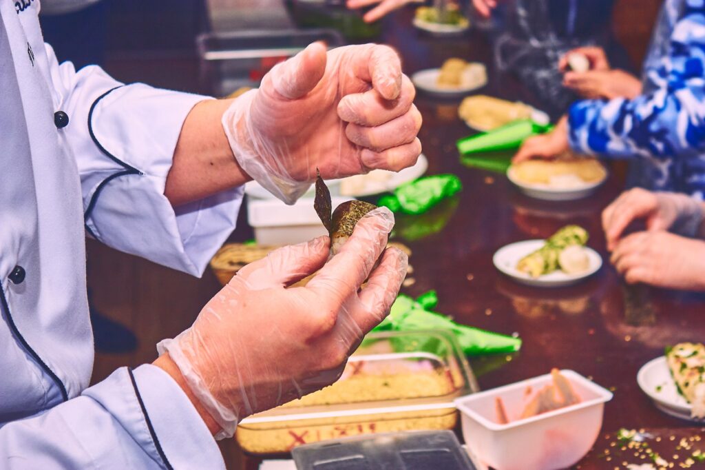 Gros plan sur un chef démontrant la préparation de finger food dans un cadre de cours de cuisine.