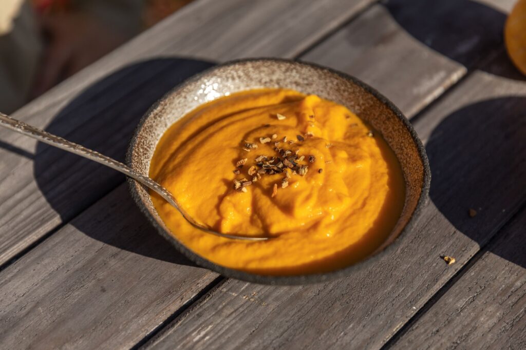Savoureuse soupe de citrouille servie dans un bol rustique sur une table en bois, parfaite pour les repas d'automne.