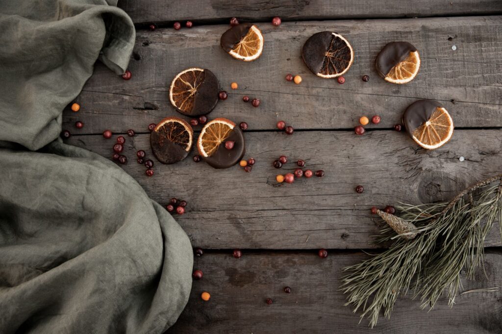Disposition à plat de décorations de Noël rustiques avec des oranges séchées et des branches de conifères.