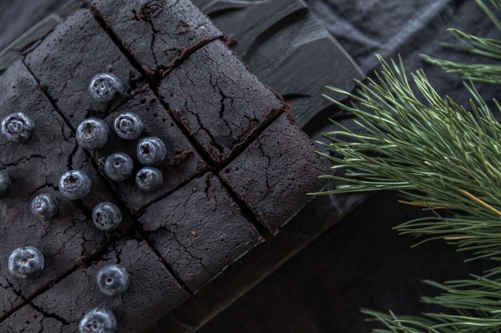 Délicieuses brownies au chocolat garnies de myrtilles fraîches, idéales pour les amateurs de desserts.