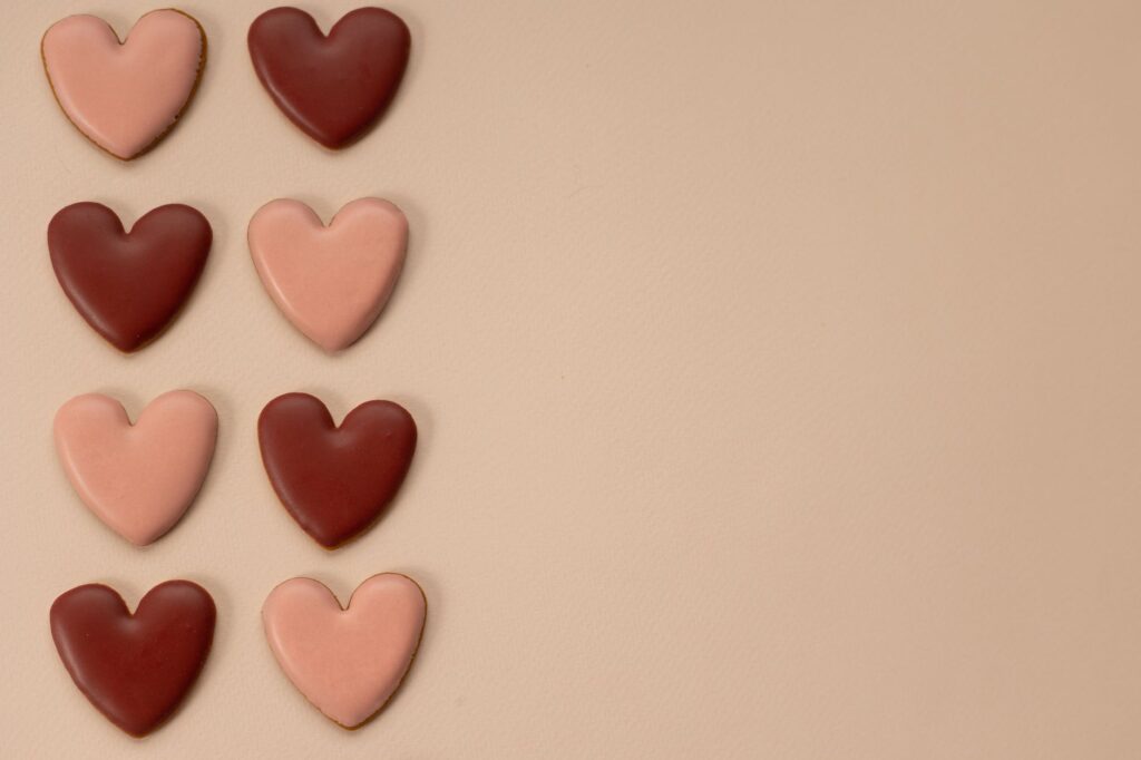 Biscuits en forme de cœur rose et marron sur un fond beige, parfaits pour la Saint-Valentin.