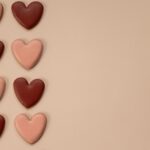 Biscuits en forme de cœur rose et marron sur un fond beige, parfaits pour la Saint-Valentin.