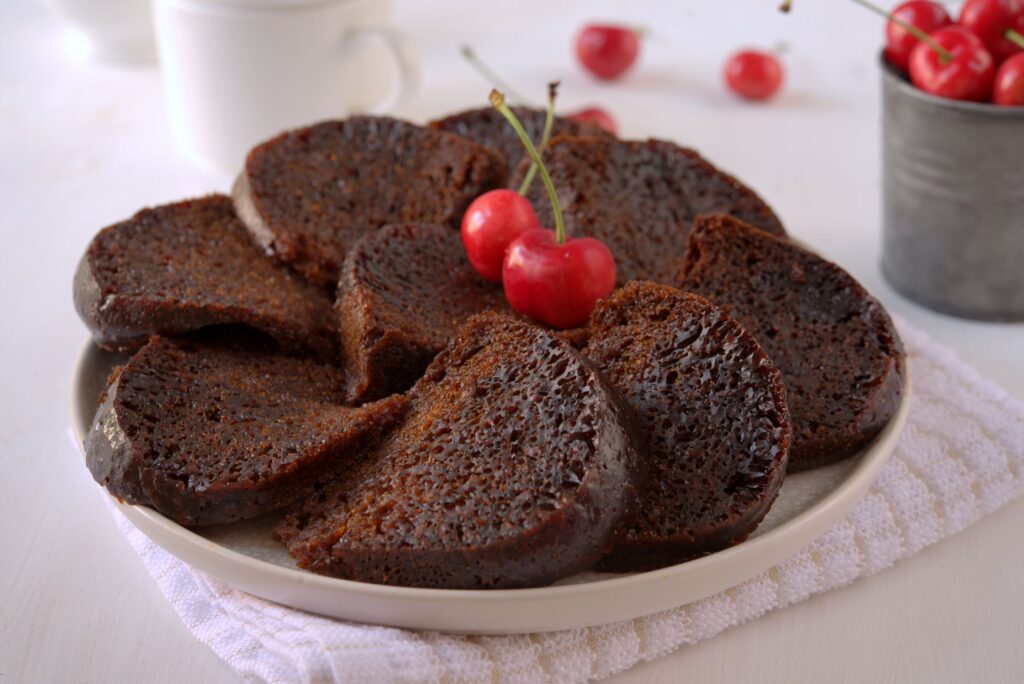 Tranches de gâteau au chocolat riche garnies de cerises fraîches sur une assiette.