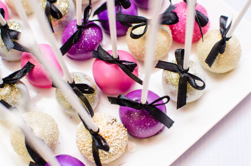 Un gros plan de cake pops vibrants décorés de rubans, parfaits pour les célébrations.