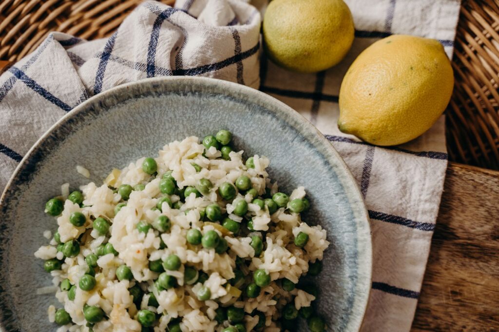 Gros plan d'un délicieux risotto aux petits pois servi avec des citrons mûrs, mettant en valeur les riches saveurs italiennes.