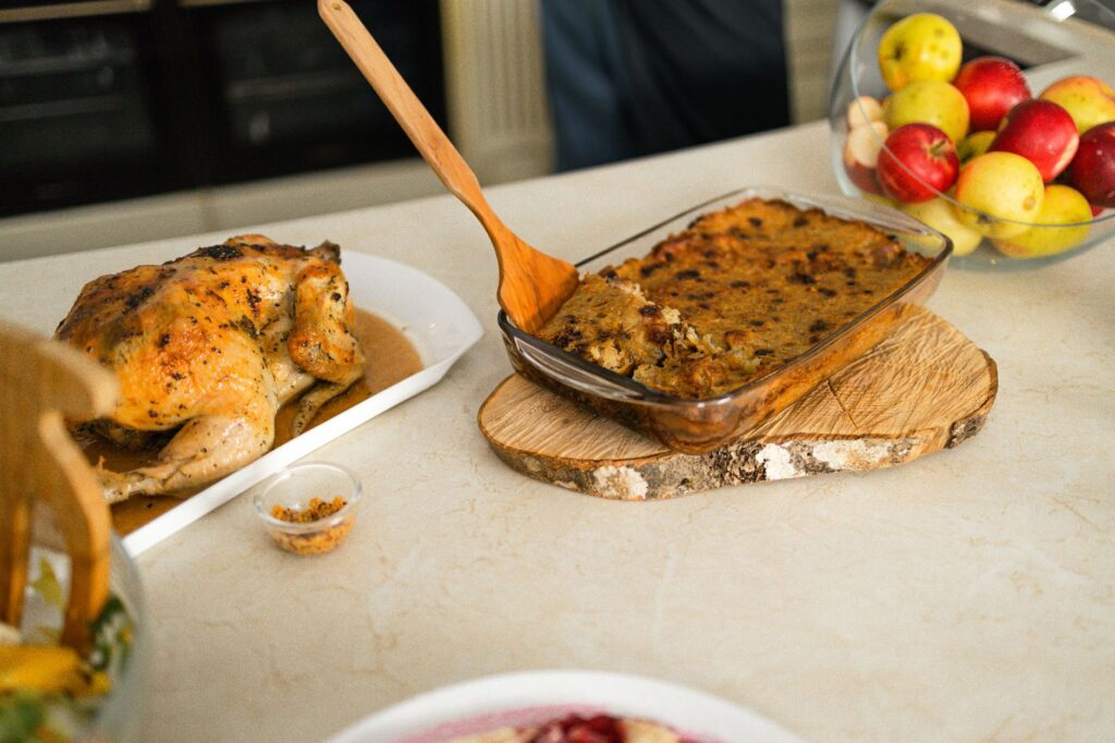 Poulet rôti appétissant servi avec une farce maison et des fruits frais sur une table.