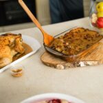 Poulet rôti appétissant servi avec une farce maison et des fruits frais sur une table.