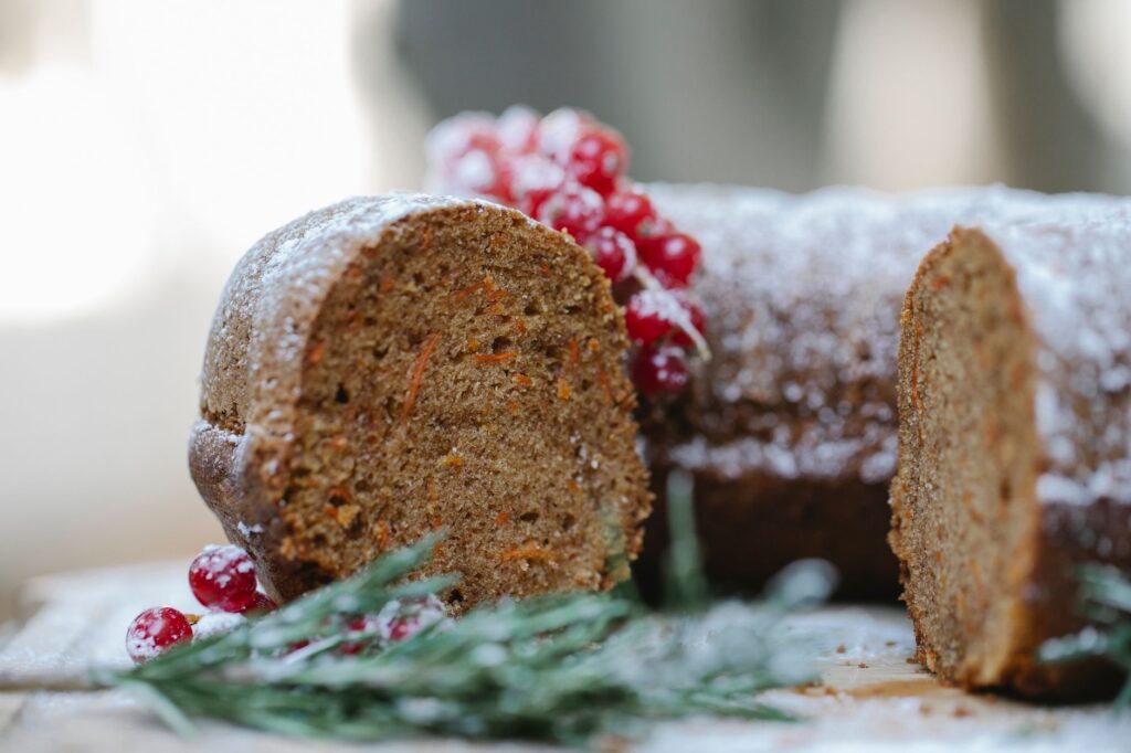 Gros plan sur un gâteau à la carotte coupé recouvert de sucre glace et de baies fraîches.