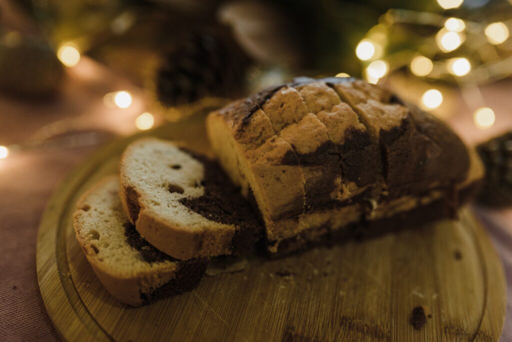 De délicieuses tranches de gâteau marbré sur une planche à découper en bois festive avec des lumières de vacances chaleureuses.