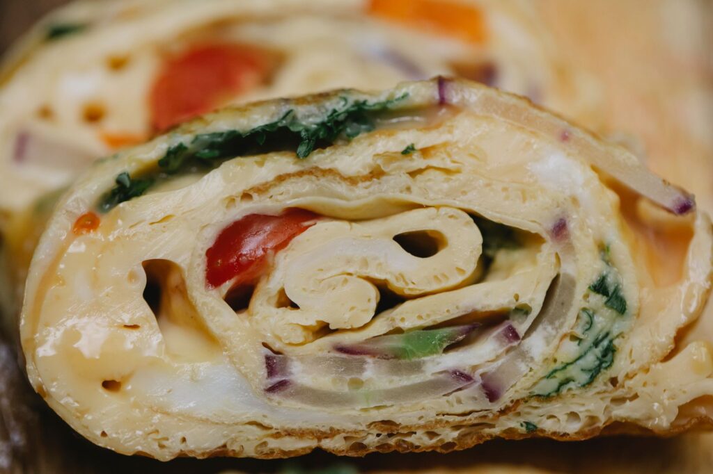 Rouleau d'omelette végétarienne tranché avec des ingrédients frais et des couleurs vives.
