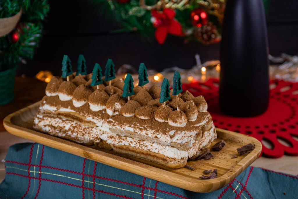 Délicieux dessert tiramisu garni de cacao et de décorations festives sur un plat en bois dans une ambiance chaleureuse.