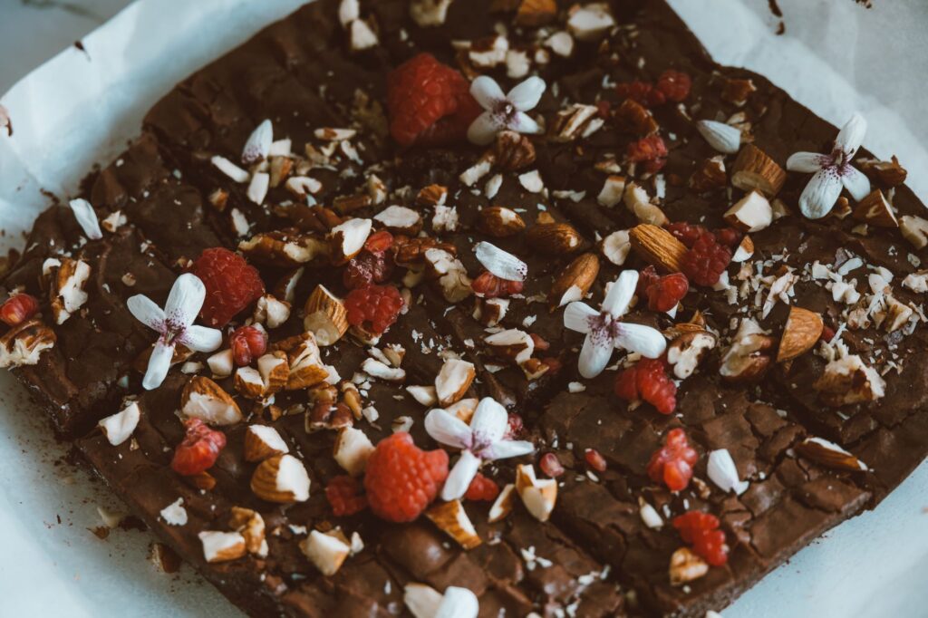 De délicieux brownies au chocolat garnis de noix, de framboises et de fleurs comestibles.