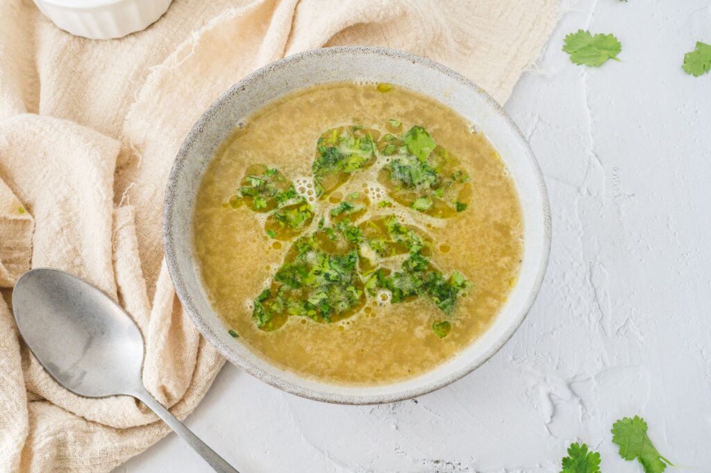 Gros plan d'un bol de soupe végétale crémeuse garni de persil, dégageant un attrait traditionnel et savoureux.