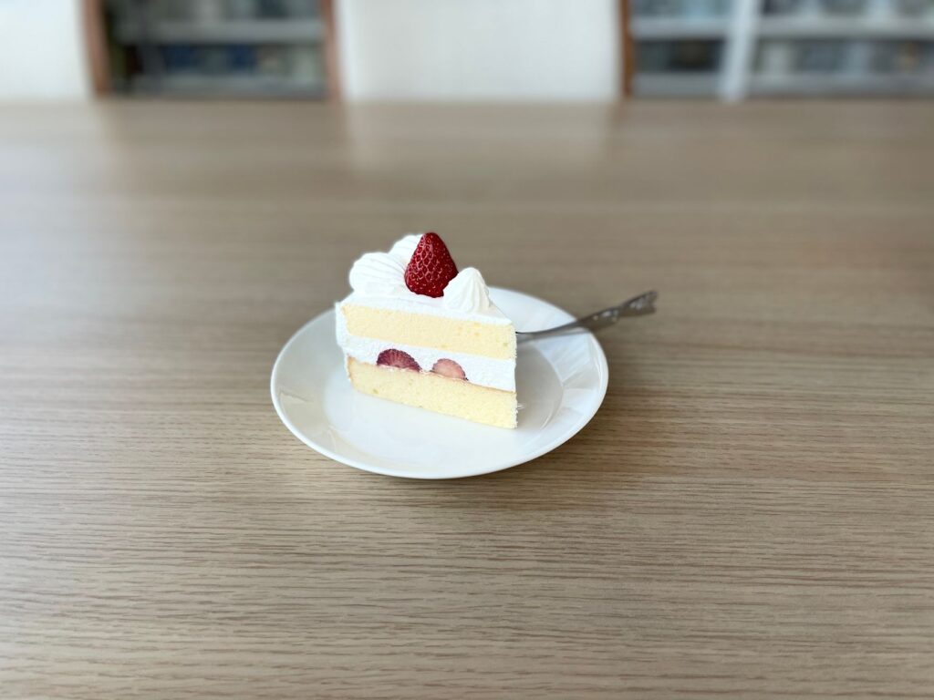 Gâteau aux fraises tranché avec de la crème fouettée sur une assiette blanche, photographié à l'intérieur.