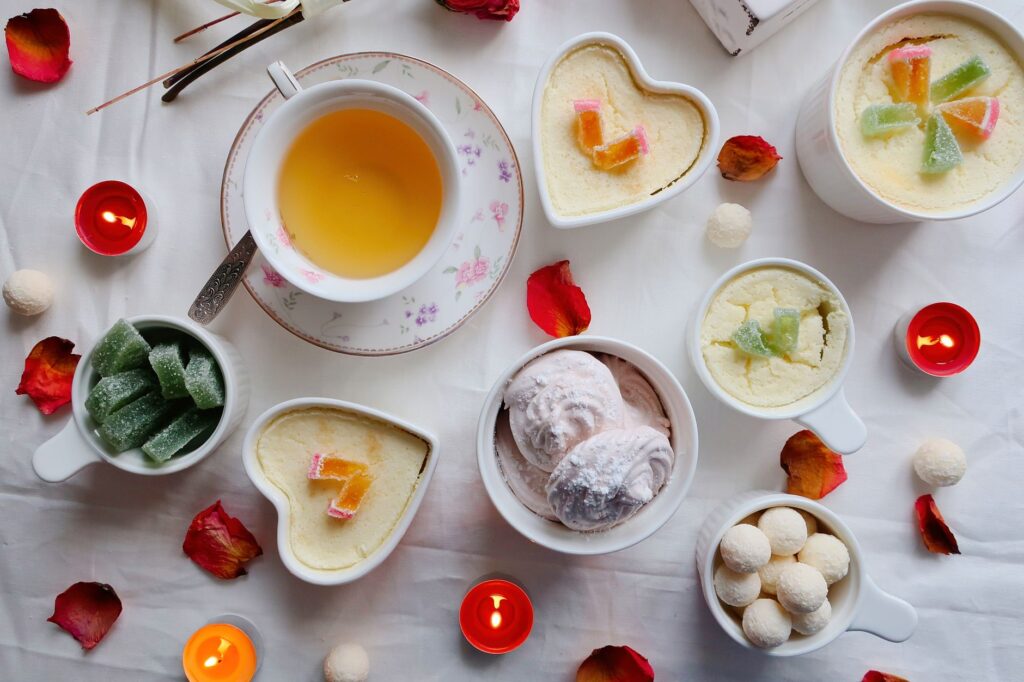 Élégante composition à plat de thé et de desserts avec des bougies et des pétales pour une atmosphère cozy.
