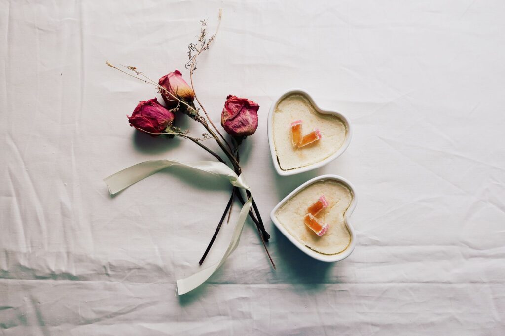 Desserts en forme de cœur avec des roses séchées sur un fond blanc. Parfait pour un thème romantique.