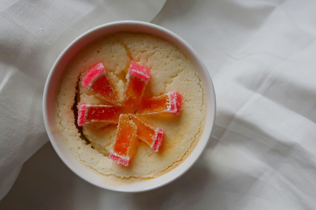 Gros plan sur un soufflé crémeux au fromage blanc dans un ramequin, garni de tranches de bonbons colorés.