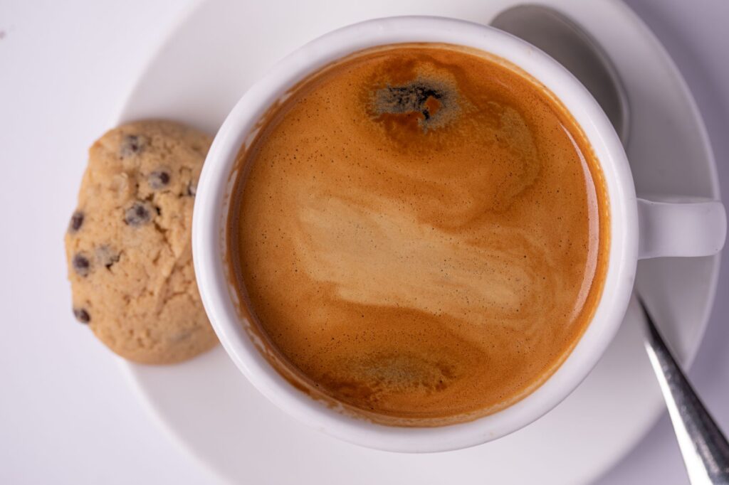 Une vue de haut vibrante d'un espresso avec un biscuit aux pépites de chocolat sur une soucoupe blanche.