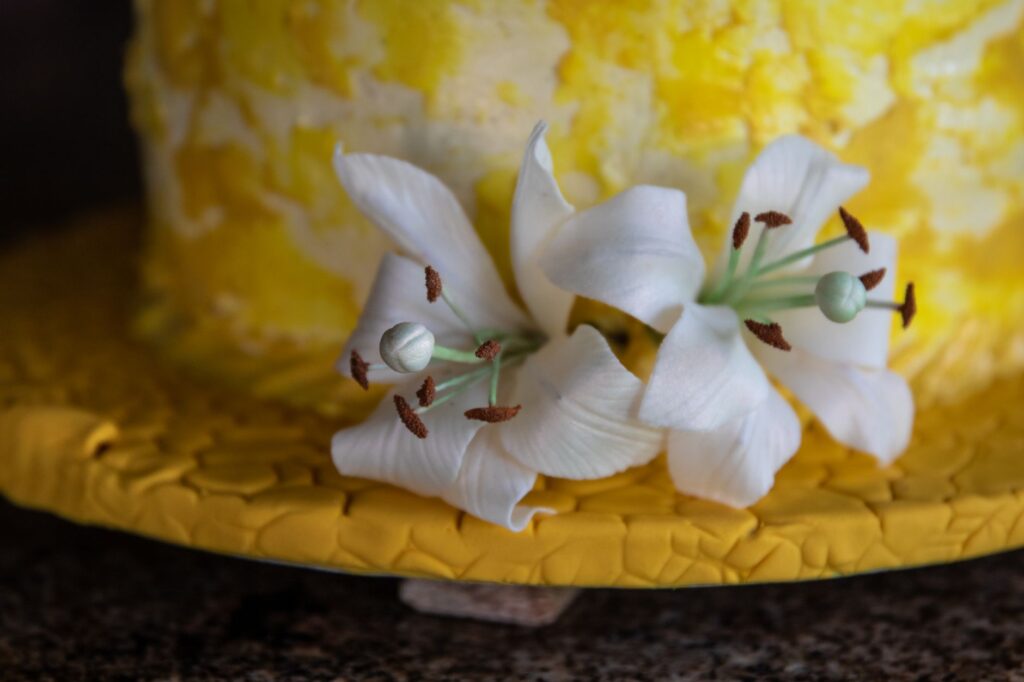 Gros plan d'un gâteau jaune avec des décorations de lys blancs, parfait pour les célébrations.