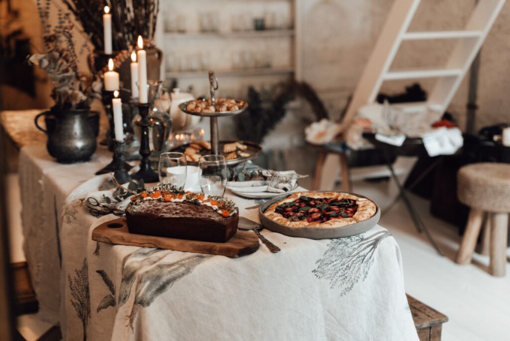 Ambiance intérieure chaleureuse avec un festin rustique, des bougies, du pain et une tarte sur une table décorée.