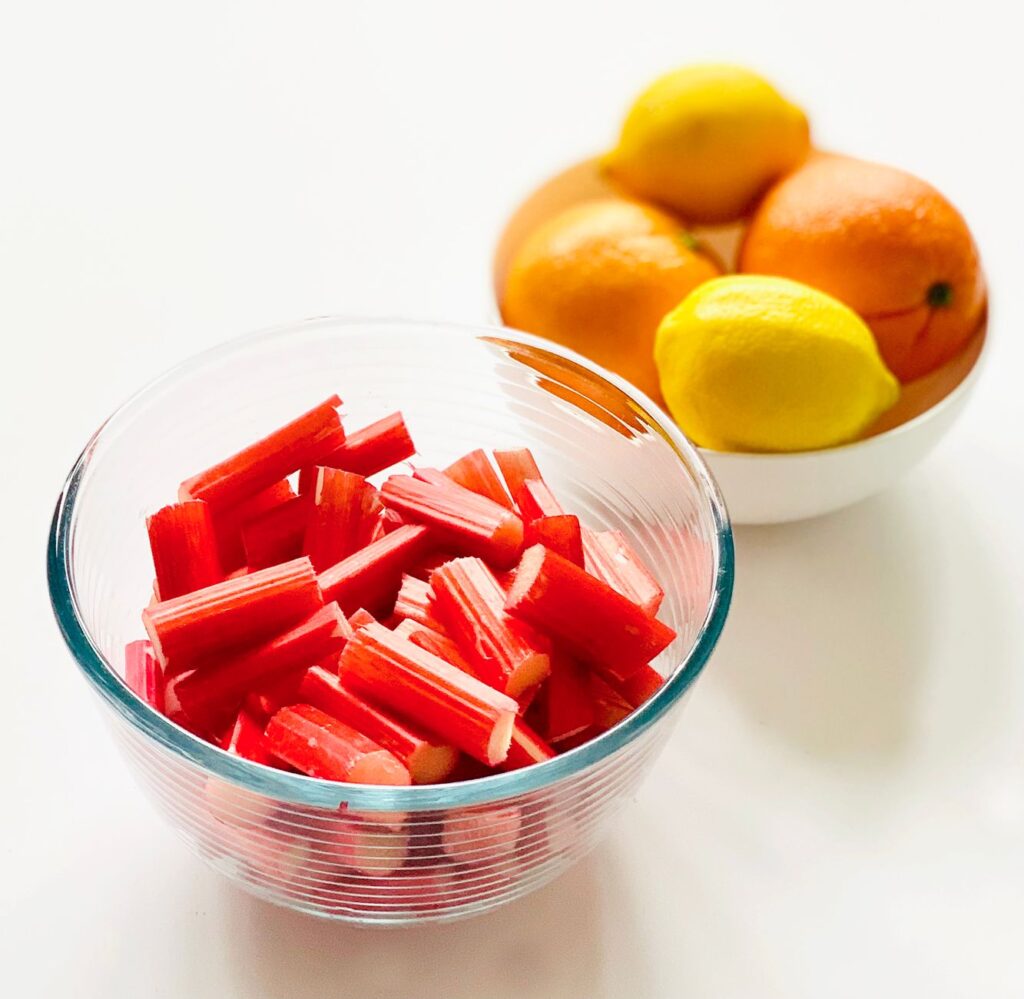 Des morceaux de rhubarbe lumineux et frais avec des agrumes dans des bols, offrant un affichage alimentaire vibrant.