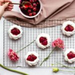 Vue de dessus de desserts à la meringue de fraise avec des cerises fraîches et des fleurs, parfaits pour le stylisme culinaire et le contenu de blog.