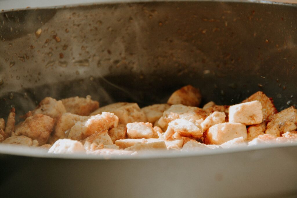 Une vue rapprochée de cubes de tofu en train de cuire dans une poêle.