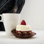 Un délicieux gâteau garni de framboises avec une tasse de café sur une table.