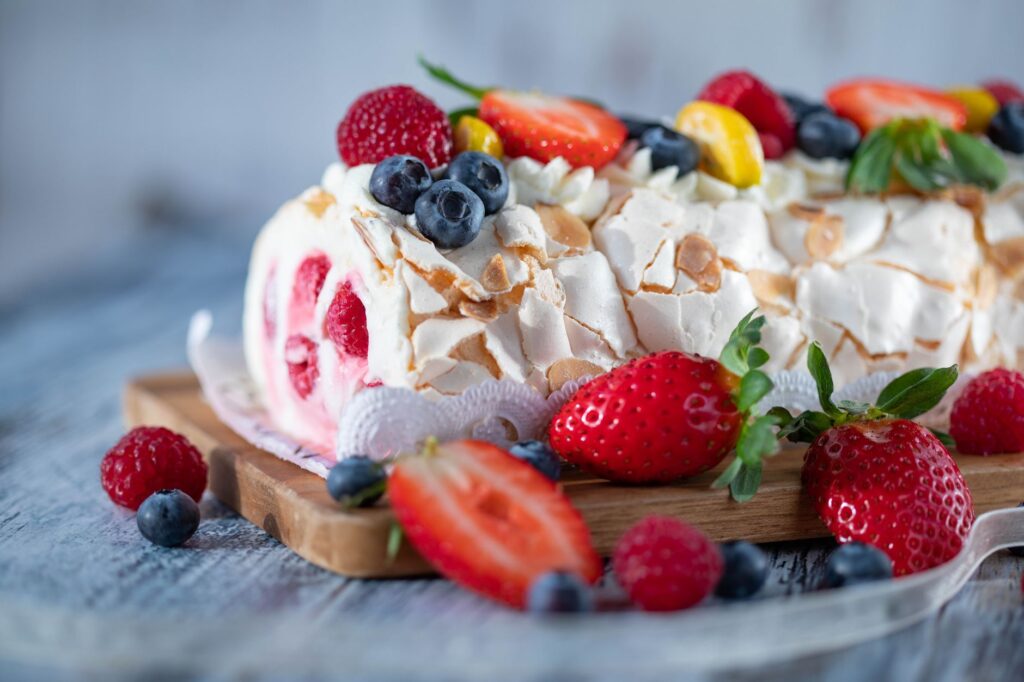 Roulade de meringue aux baies tentante avec des fraises fraîches, des myrtilles et des framboises.