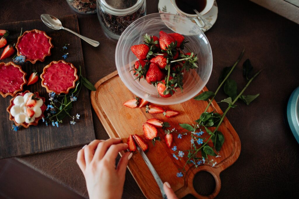 Vue de dessus de fraises fraîches coupées sur une planche en bois, parfaites pour des desserts délicieux.